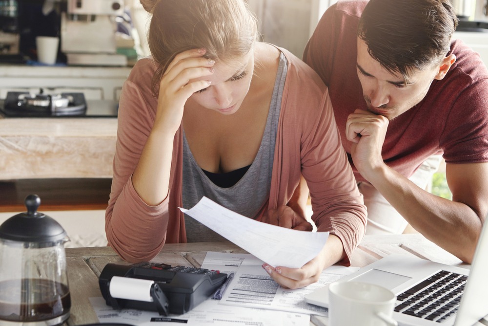 Young,Couple,Calculating,Their,Domestic,Budget,Together,In,Kitchen,,Trying